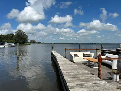 a dock with a bench and a boat on the water at Holiday Home Assum by Interhome in Uitgeest