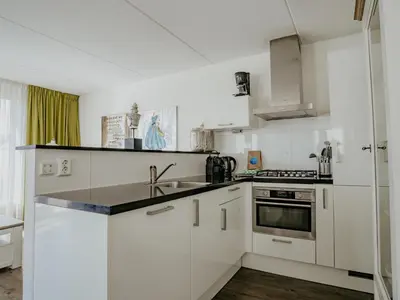 a white kitchen with a sink and a stove at Holiday Home Assum by Interhome in Uitgeest