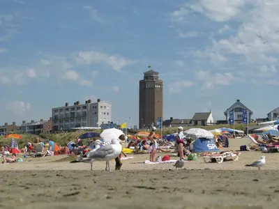 a group of people on a beach with a clock tower at Pension Zee en Duinzicht in Zandvoort