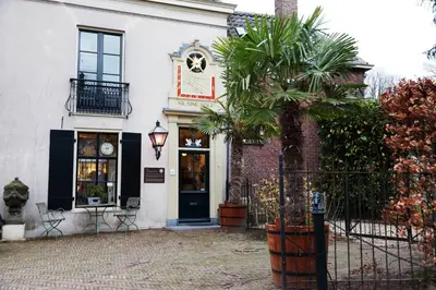 a white building with a black door and a palm tree at Logement Swaenenvecht in Utrecht
