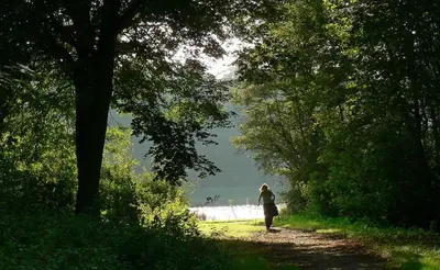 a woman walking down a dirt path near the water at Motorjacht Flint in Amsterdam