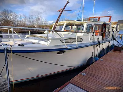 a white boat is docked at a dock at Motorjacht Flint in Amsterdam