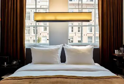 a bed with white pillows in front of a window at Sir Albert Hotel, part of Sircle Collection in Amsterdam