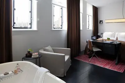 a bathroom with a tub and a chair and a desk at Sir Albert Hotel, part of Sircle Collection in Amsterdam