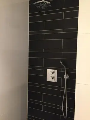 a bathroom with a shower with black tiles at Zeesterflat 117 in Egmond aan Zee