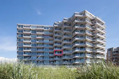 a tall apartment building with a red window at Zeesterflat 117 in Egmond aan Zee