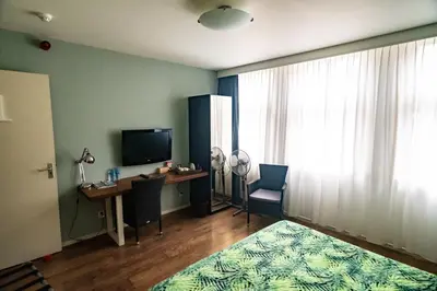 a room with a desk and a television and a bedroom at B&B Posthoorn in Hoorn