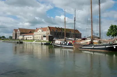 two boats are docked in a river near a building at B&B Posthoorn in Hoorn