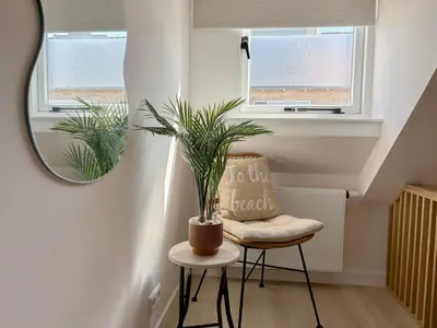 a plant sitting on a stool in a room with two windows at Casa Bon Bini in Egmond aan Zee