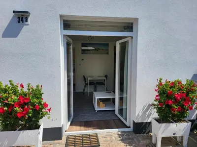 a door leading to a patio with red flowers at FlipFlop in Noordwijk aan Zee