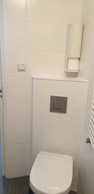 a bathroom with a white toilet and a white tiled wall at FlipFlop in Noordwijk aan Zee