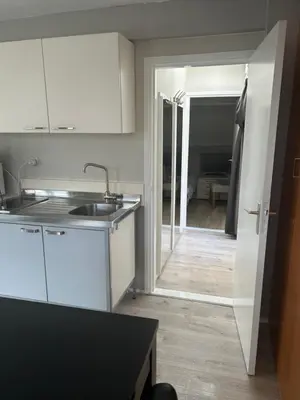 a kitchen with a sink and a door to a room at Apartment at the Beach in Noordwijk aan Zee