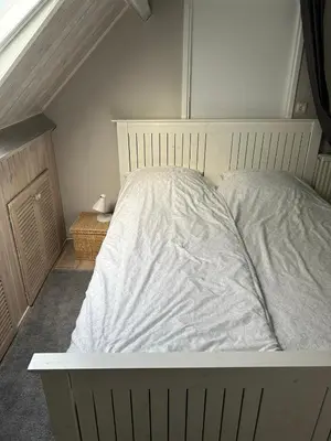 a bedroom with a bed with white sheets on it at Apartment at the Beach in Noordwijk aan Zee