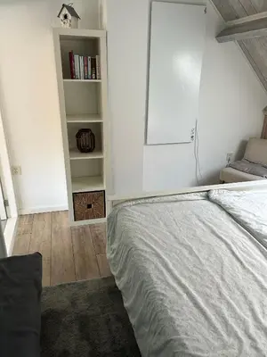 a bedroom with a bed and a book shelf at Apartment at the Beach in Noordwijk aan Zee