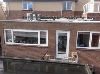 a brick house with a dog sitting on a balcony at Apartment at the Beach in Noordwijk aan Zee