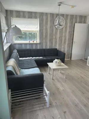 a living room with a black couch and a table at Apartment at the Beach in Noordwijk aan Zee