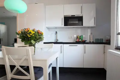 a kitchen with white cabinets and a table with a vase of flowers at 4 Seasons Zandvoort in Zandvoort
