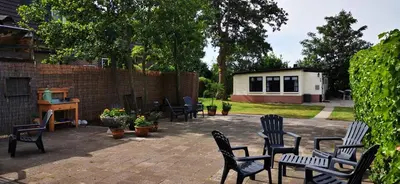 a patio with chairs and tables and a building at Bed & Breakfast Prins Hendrik (Zuidschermer) in Zuidschermer