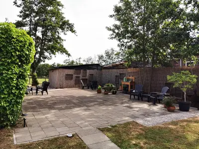 a patio with chairs and tables and a brick wall at Bed & Breakfast Prins Hendrik (Zuidschermer) in Zuidschermer