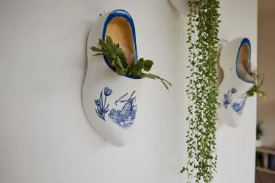 a white vase with a plant in it on a wall at Treehouse Inn in Duivendrecht