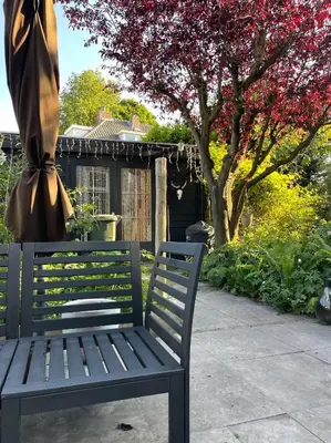 a blue bench sitting under a umbrella on a patio at Stylish * Sunny * Cosy House in Heemstede