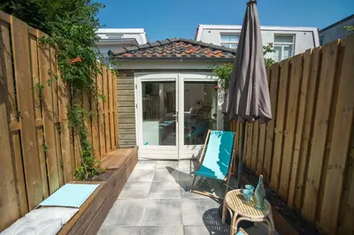 a patio with an umbrella and a chair and a table and an umbrella at The Bond Studio FREE PARKING in Zandvoort