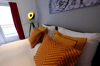a bed with orange and white pillows and a window at Citycenter Residence in Amsterdam
