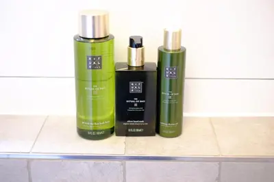 three green shampoo bottles sitting on a tile counter at Citycenter Residence in Amsterdam