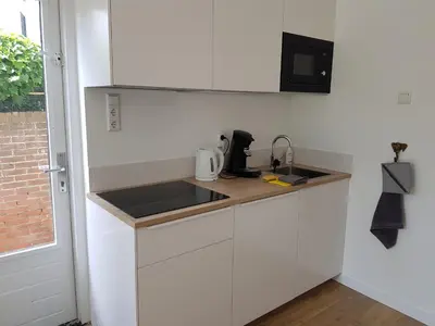 a white kitchen with a sink and a microwave at Picco Bello in Zandvoort