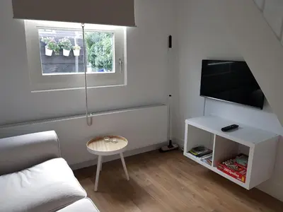 a living room with a couch and a tv and a table at Picco Bello in Zandvoort