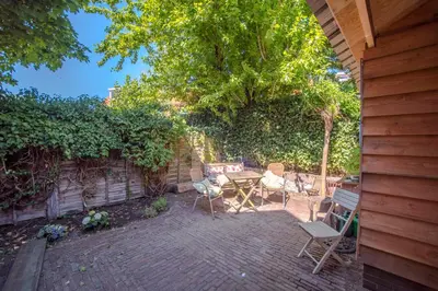 a patio with chairs and a table and a tree at Ocho in Zandvoort
