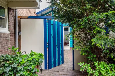 an open gate to a house with blue doors at Ocho in Zandvoort