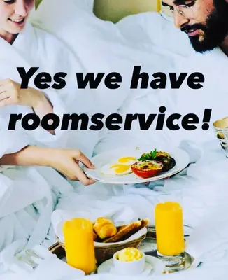 a man and woman in bed with a plate of food at Bed & Breakfast Jo Amsterdam in Amsterdam