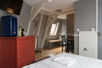 a bedroom with a bed and a dresser and a kitchen at Westerpark Suites in Amsterdam