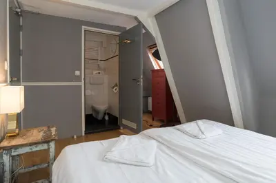 a bedroom with a white bed and a bathroom at Westerpark Suites in Amsterdam