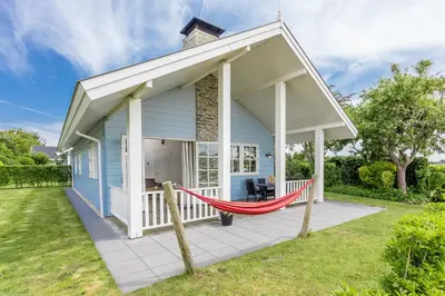 a house with a hammock on the front porch at De Gouden Spar in Noordwijk