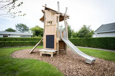 a wooden playground with a slide in a yard at De Gouden Spar in Noordwijk