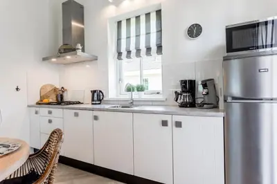 a kitchen with white cabinets and a sink and a table at De Gouden Spar in Noordwijk