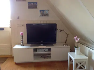 a tv on a dresser in a living room at De Slotruine in Egmond aan den Hoef
