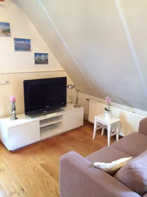 a living room with a flat screen tv on a white cabinet at De Slotruine in Egmond aan den Hoef