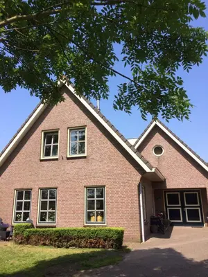 a brick house with windows and a tree at De Slotruine in Egmond aan den Hoef