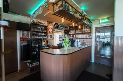 a bar in a restaurant with a vase on the counter at Hotel Faber in Zandvoort