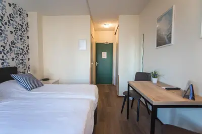 a room with two beds and a desk and a table at Hotel Faber in Zandvoort