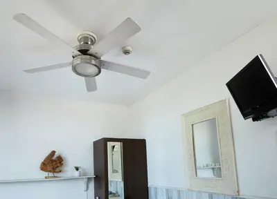 a ceiling fan and a television in a living room at Guest House Aquarius in Zandvoort