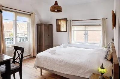 a bedroom with a bed and a desk and windows at Guest House Aquarius in Zandvoort