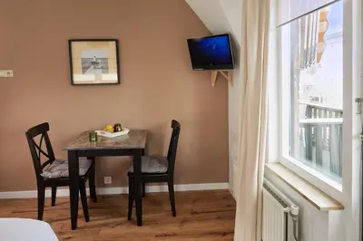 a dining room table with chairs and a tv on the wall at Guest House Aquarius in Zandvoort
