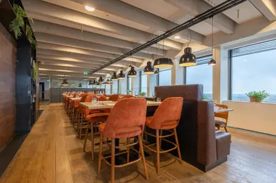a dining room with tables and chairs and windows at Leonardo Hotel Amsterdam Rembrandtpark in Amsterdam