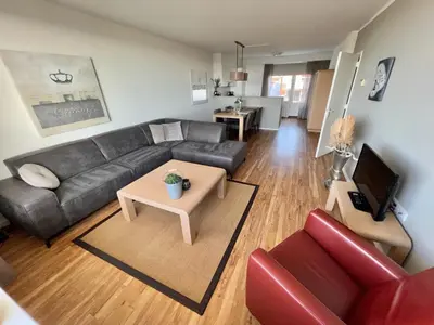 a living room with a black couch and a table at Appartementen Zeezicht in Katwijk aan Zee