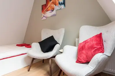 a bedroom with two chairs and a bed with a red pillow at Saint Claire Studio's in Amsterdam