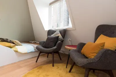 a room with two chairs and a bed and a window at Saint Claire Studio's in Amsterdam
